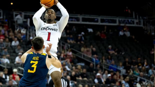 Cincinnati Bearcats guard Day Day Thomas (1) hits a jump shot as West Virginia Mountaineers guard Kerr Kriisa (3) defends in the first half of the Big 12 Conference tournament between Cincinnati Bearcats and West Virginia Mountaineers at T-Mobile Center in Kansas City, Mo., on Tuesday, March 12, 2024.